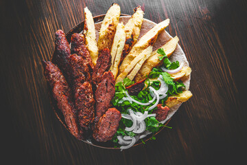 cut Lulia kebab with potato in plate on wooden table background
