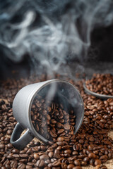 Gray cup full of steaming coffee beans on a dark gray stone background