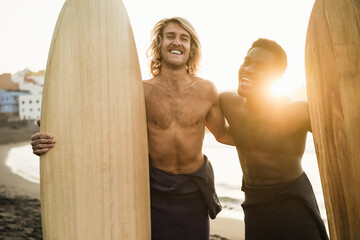 Happy multiracial surfers having fun on the beach after surf session - Focus on left face