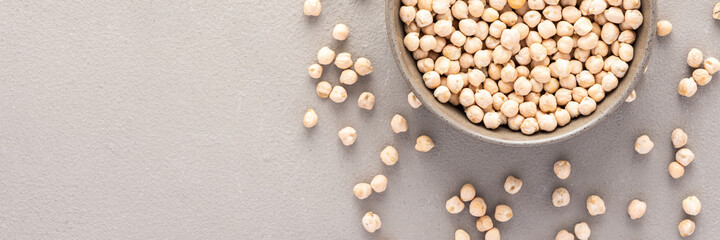 Legumes in bowl and scattered in the background, chickpeas in a plate banner, top view, copy space