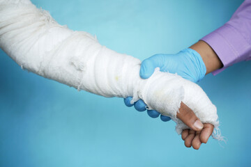doctor hand in gloves holding injured painful hand with bandage 
