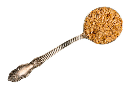 golden flax seeds in silver tablespoon cutout