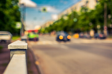 Summer in the city, the car rides down the street with trees. Close up view from the handrail on the sidewalk level