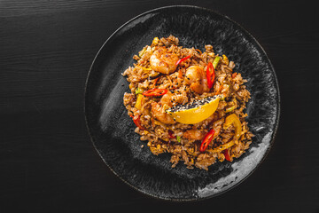 Fried rice with shrimp and vegetables in plate on wooden table background