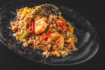 Fried rice with shrimp and vegetables in plate on wooden table background