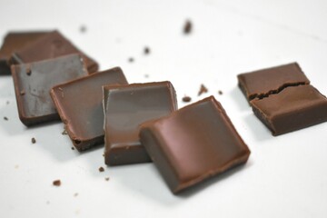 luxury handmade chocolates and a heart shaped praline on a twirling gold ribbon over white background with vignette and copy space