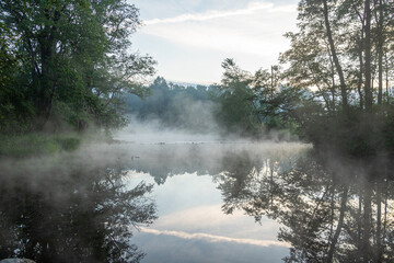 Early morning scene at the river Liela Jugla with fog over the water in June in Latvia