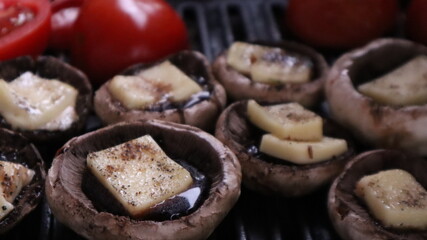 Grilled mushrooms with cheese, tomatoes  and eggplant on the hot flaming charcoal grill. Champignon white mushrooms, onions and tomatoes grilled on grill with hot coal