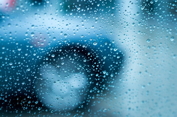 Traffic in rain. A blurred car front side detail through a wet car window during a rain. Low DOF.