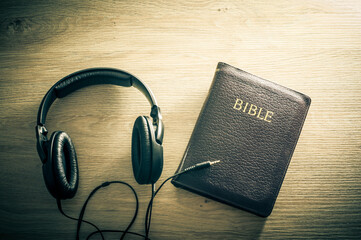 Bible and headphones on wooden background