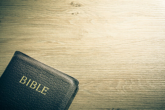 Bible and paper on wooden table background with large copy space