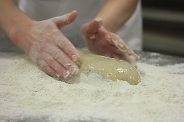 Woman's hands kneading the bread dough. Making dough by female hands on wooden table