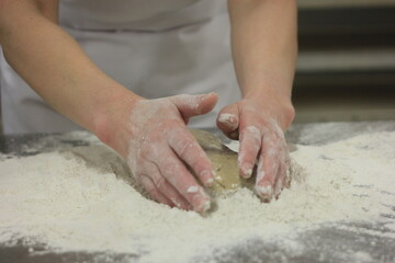 Fototapeta premium Woman's hands kneading the bread dough. Making dough by female hands on wooden table