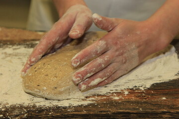 Woman's hands kneading the bread dough. Making dough by female hands on wooden table