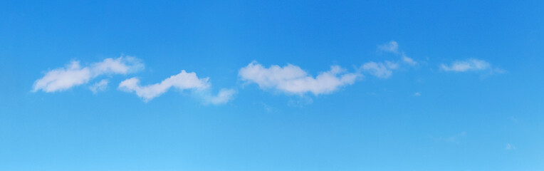 Small white clouds in the blue sky in sunny weather