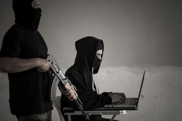 Terrorist team with anonymous hacker stealing data from laptop. Cyber security concept.
