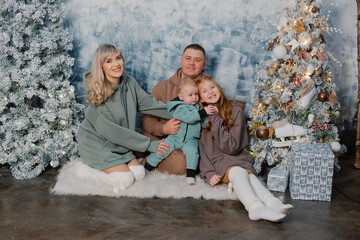 Beautiful and happy family at the New Year tree at a photo shoot.