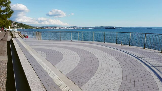 Terrace on the Barcola seafront in Trieste, Italy, during a glorious springtime afternoon, with the city skyline in the background