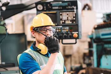 Work at factory.Asian worker man  working in safety work wear with yellow helmet and glasses l ear muff using walkie talkie .male technician asia in factory workshop industry machine professional
