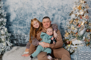 Happy father with his teenage daughter and little son by the tree.