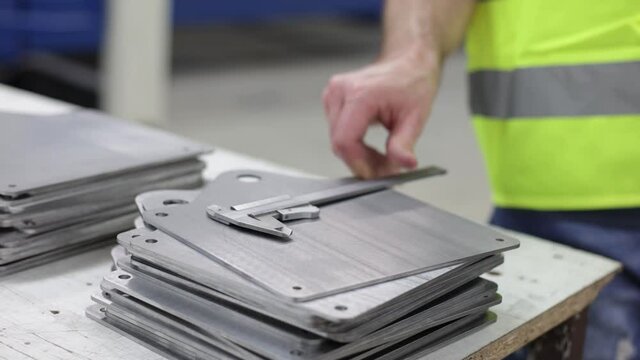 Qualit&auml;tskontrolle an einem St&uuml;ck Metall mit dem Messschieber - Metallteile