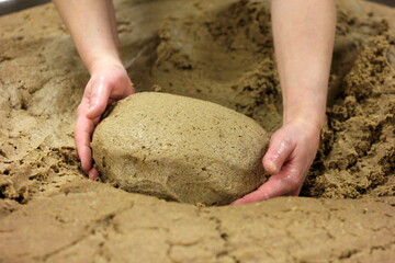 homemade bread dough made and formed by hand a large pot. Woman's hands kneading the bread dough.