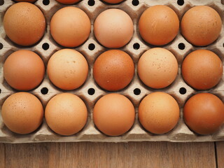 Brown chicken eggs top view close-up in carton box on the wooden table background.