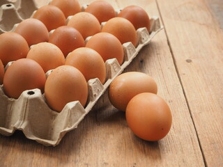 Brown chicken eggs close-up in carton box on the wooden table with text area space, wooden background.