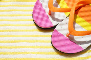 Colored beach flip flops on a striped towel. Positive summer still life. View from above.