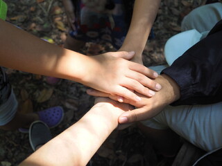 A close-up of the handshake of four best friends (hand stack) before doing a joint activity. A view of cooperation for the success of the group
