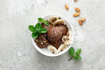 Chocolate and banana fruit ice cream with almond nuts served in bowl, top view