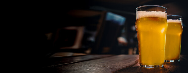 two glass of light beer stands on a table in a bar or pub