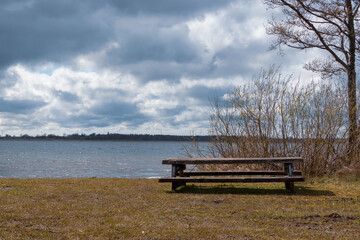 View of the shore of Lake Durbe with a tourist picnic lounge wooden table in the hall. Small waves in the water.