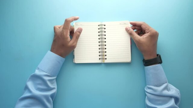 top view of man's hand turning a pager of a diary 