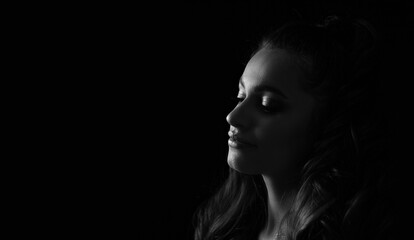 Monochrome portrait of a sensual young woman posing at the black background