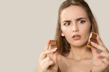 Frightened young brunette woman looking on pieces of chocolate