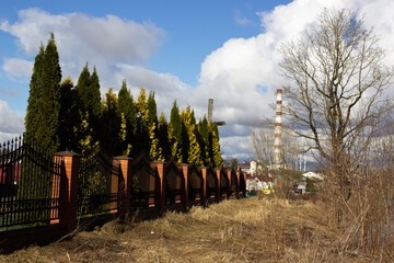landscape with trees, hedge, factory chimney and dry grass