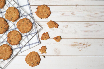 Pumpkin seed and sesame cookie on cooling rack and napkin on white wooden background with coppy space on right.