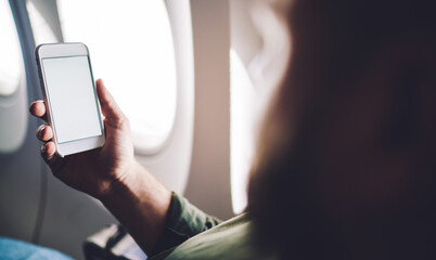Faceless man using cellphone while flying on plane