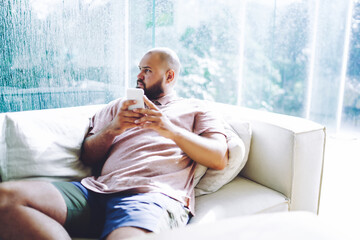 Overweight man with smartphone on sofa - obrazy, fototapety, plakaty