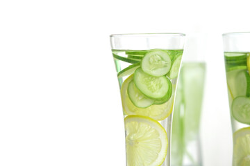 Close up of glass of detox water with cucumber and lemon on white background with copy space on left.
