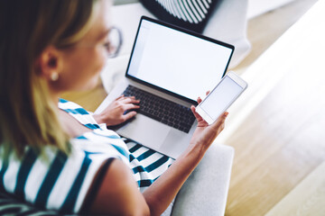 Woman watching funny video on smartphone while working on laptop