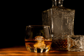 Whiskey in glass with ice on dark background.