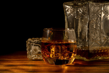 Whiskey in glass with ice on dark background.
