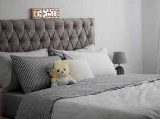 bedroom with grey set of bed and decorative teddy bear