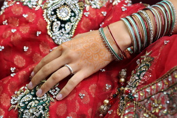 Fototapeta na wymiar junge Hand mit schönem indischen Schmuck und vielen Amreifen auf rotem Tuch