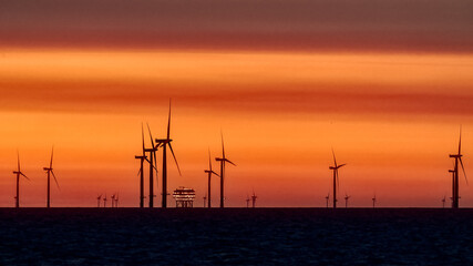 Obraz premium Offshore Wind Turbines and rig set against a sunrise red sky