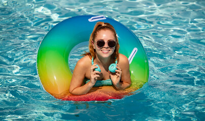 Summer Vacation. Enjoying suntan. Woman in swimsuit on inflatable circle in the swimming pool headphones music.