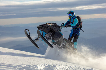 snowmobile. a guy rides a snow bike in the mountains against the backdrop of a ridge of rocks and a...