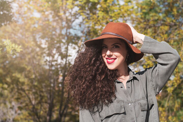 Portrait young woman with curly hair and a hat in a park. Latin woman. Arabian woman.